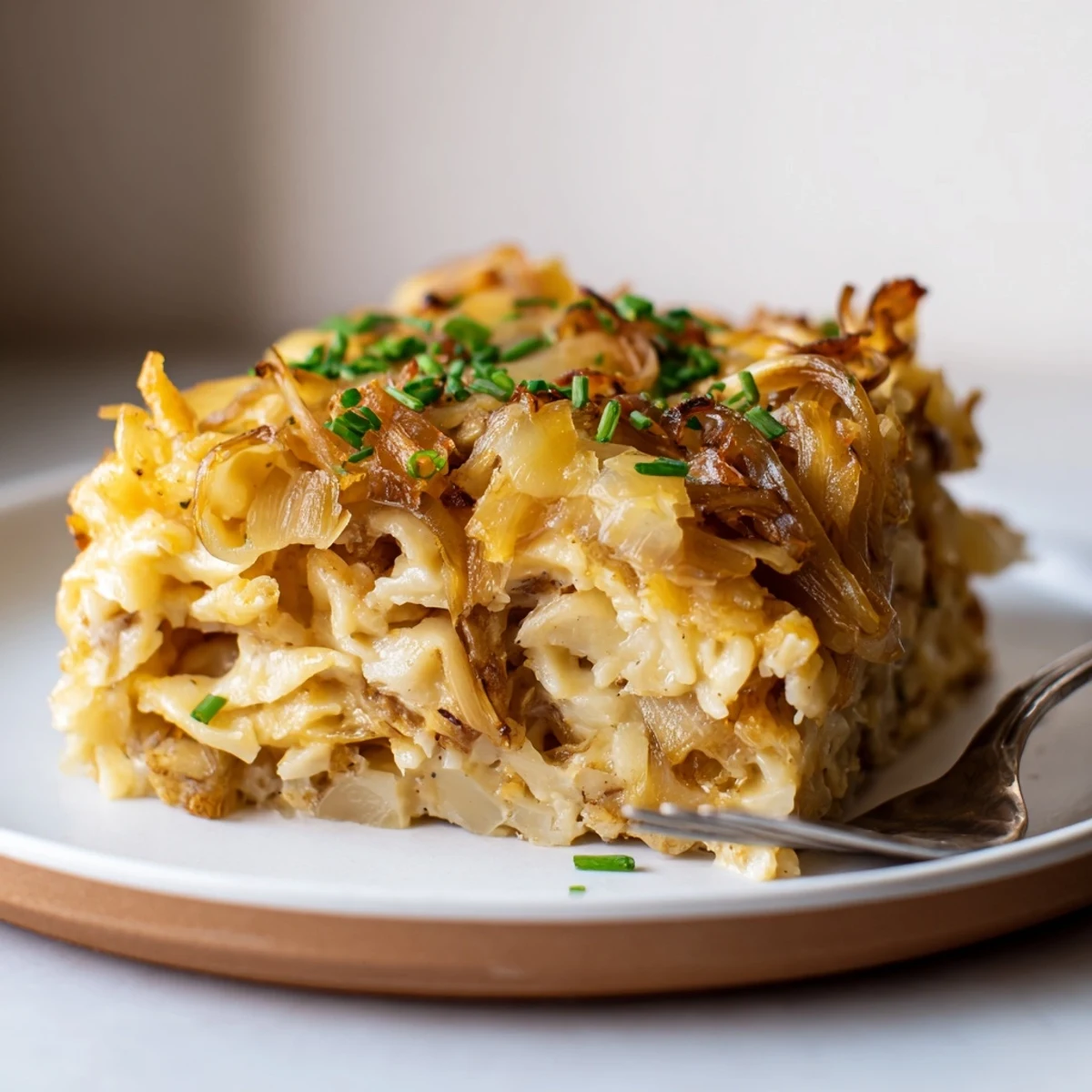 Baked Cheesy Spaetzle in einer goldenen, käsigen Auflaufform mit karamellisierten Zwiebeln.  
