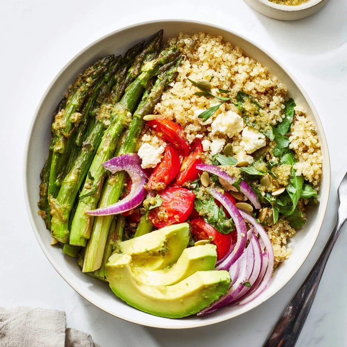 Schalen mit Quinoa und Spargel, belegt mit frischen Gemüse und Zitronen-Tahini-Dressing.  