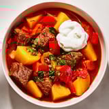 Nahaufnahme: Eine Schüssel German One-Pot Goulash, reichhaltig, mit Paprika, Rindfleisch, Kartoffeln.