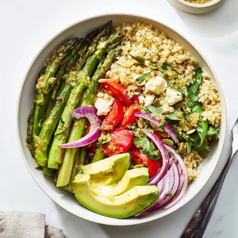 Schalen mit Quinoa und Spargel, belegt mit frischen Gemüse und Zitronen-Tahini-Dressing.  